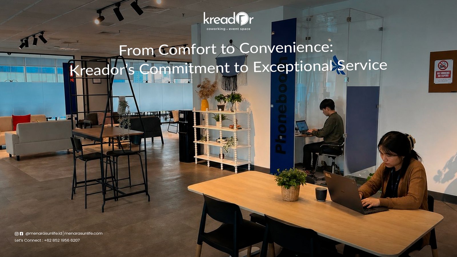 Two professionals working at their desks in a modern coworking space at Kreador, featuring comfortable seating and a phone booth for private calls.